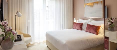 A modern bedroom with a large bed, a bedside table, a lamp, and a painting on the wall.
