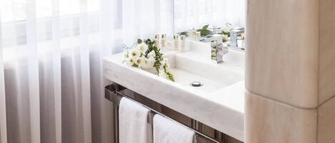 A bathroom with a marble sink, a large mirror, and a towel rack.