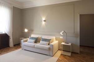 A modern living room with a sofa, two side tables, and a wall-mounted light fixture.