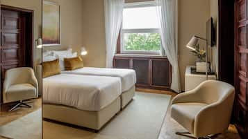 Une chambre d’hôtel avec un grand lit, deux tables de chevet, une chaise, une fenêtre avec des rideaux et un miroir.
