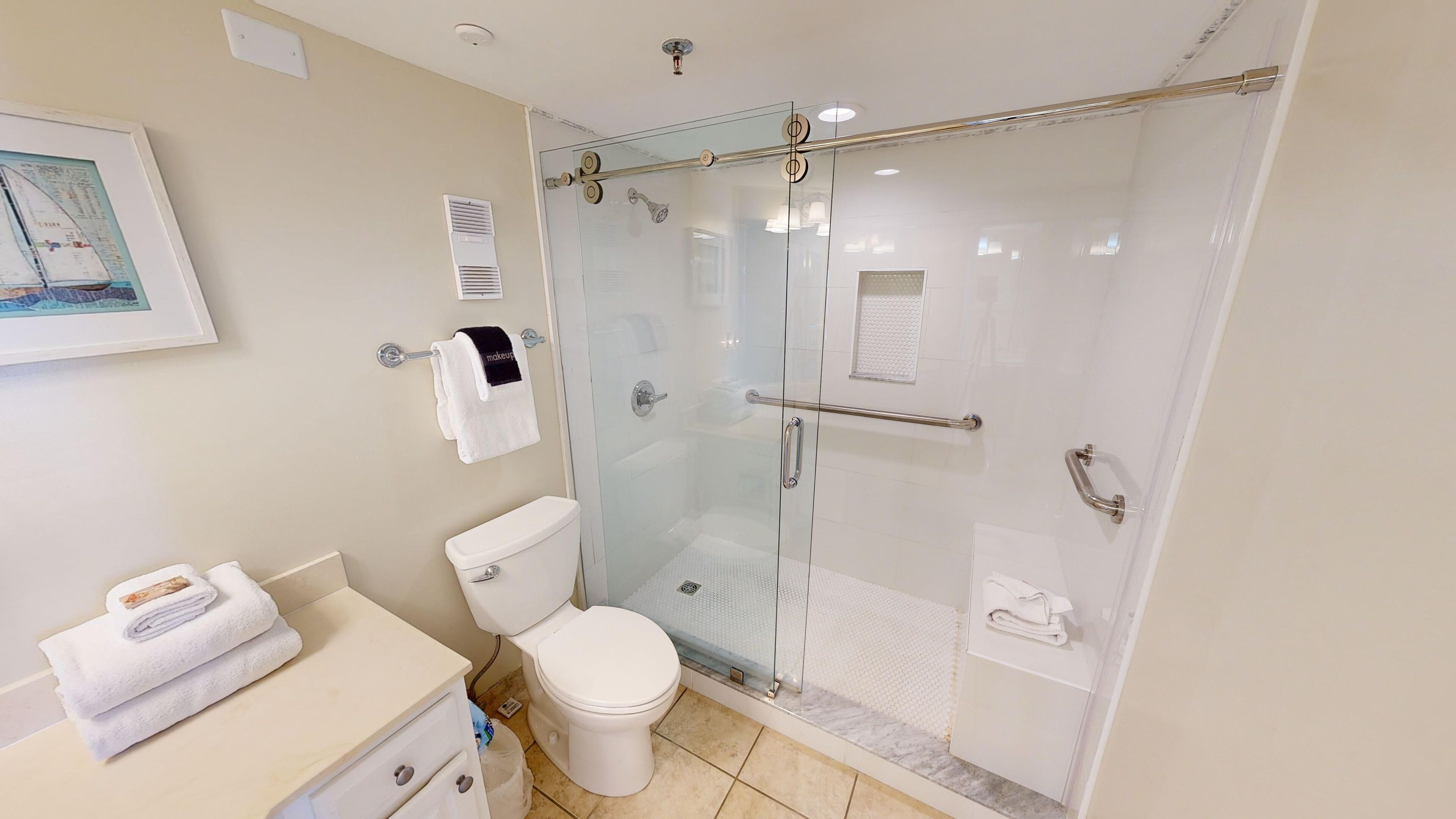 A modern bathroom with a glass-enclosed shower, a toilet, and a vanity with a sink and towel rack.