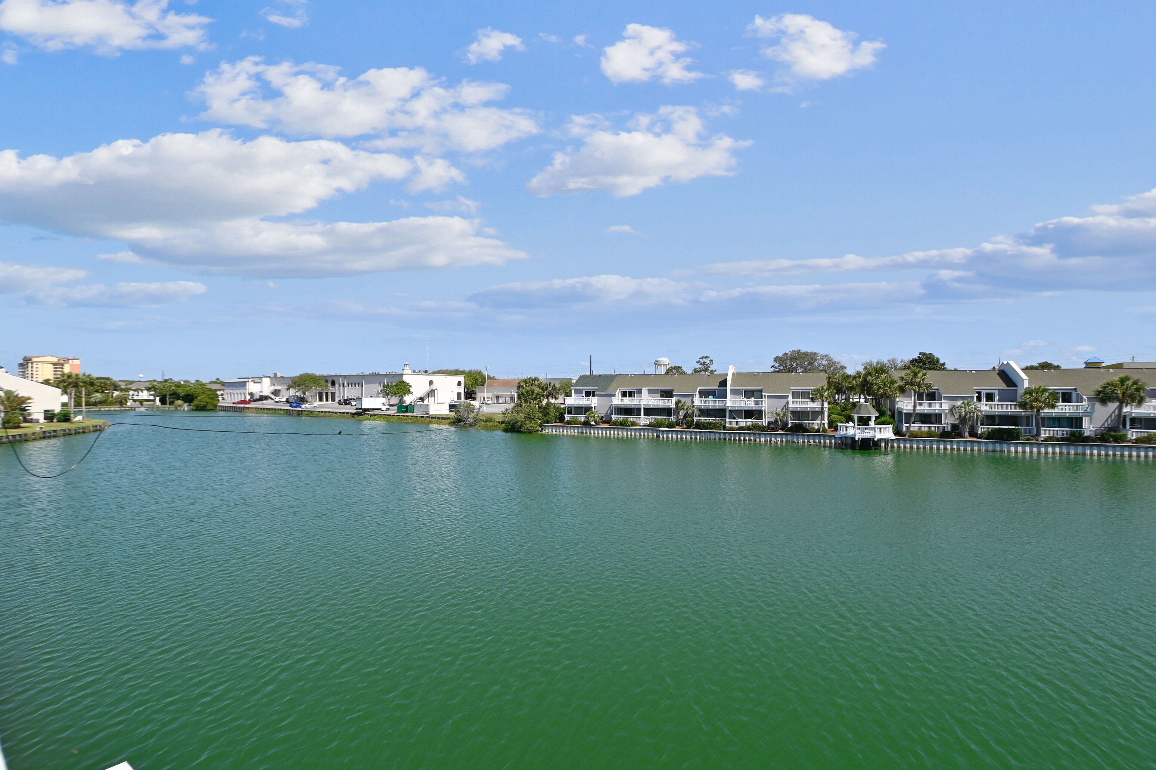 A waterfront property with a row of buildings along the water, featuring balconies and a clear view of the lake.