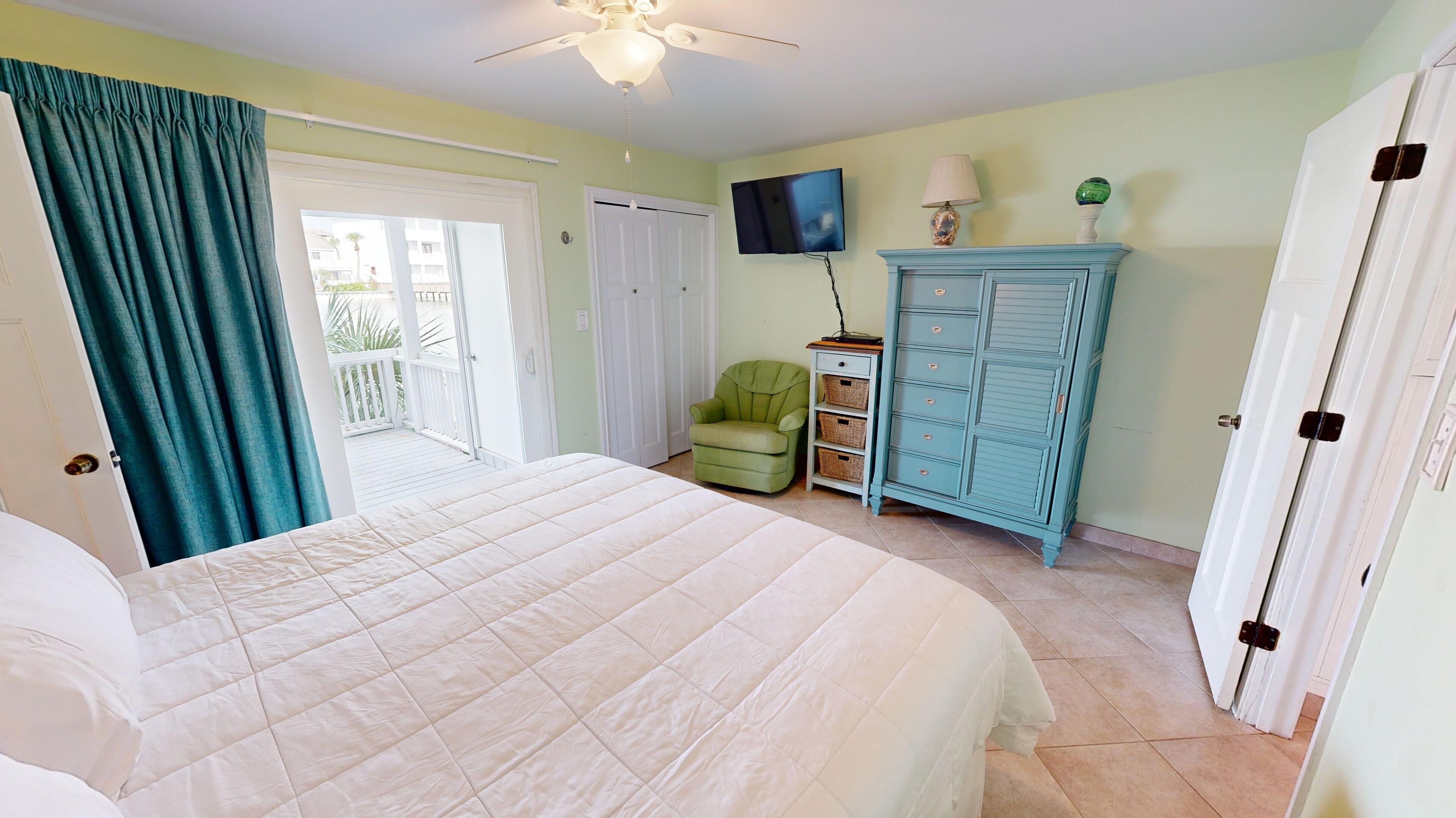 Un dormitorio con cama, una silla, un televisor y un armario.