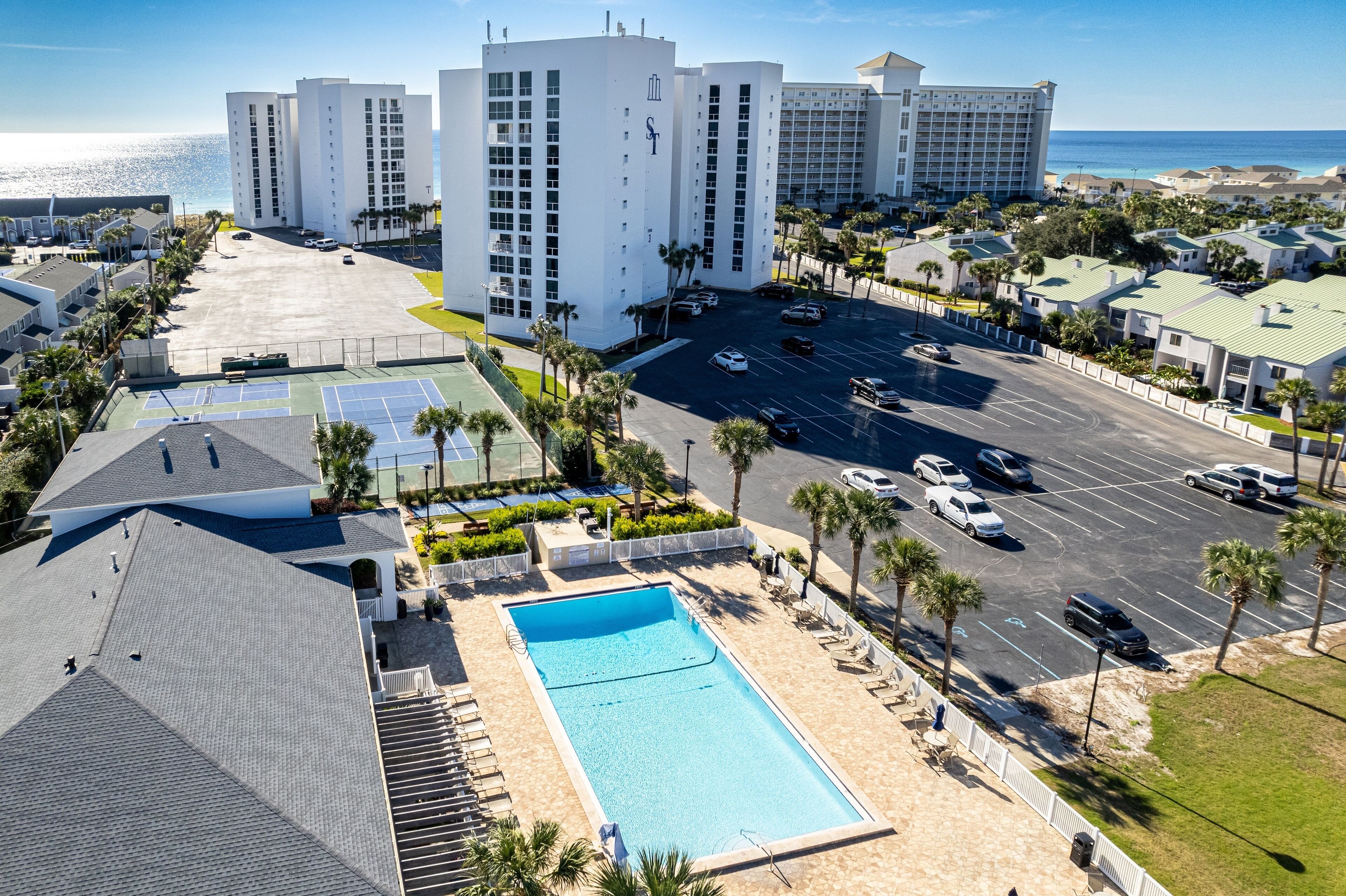 Un hotel con varias construcciones, piscina y estacionamiento.