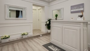 Un pasillo con una puerta blanca, un espejo y un letrero que dice 'CHARME & CHIC LIVING'.