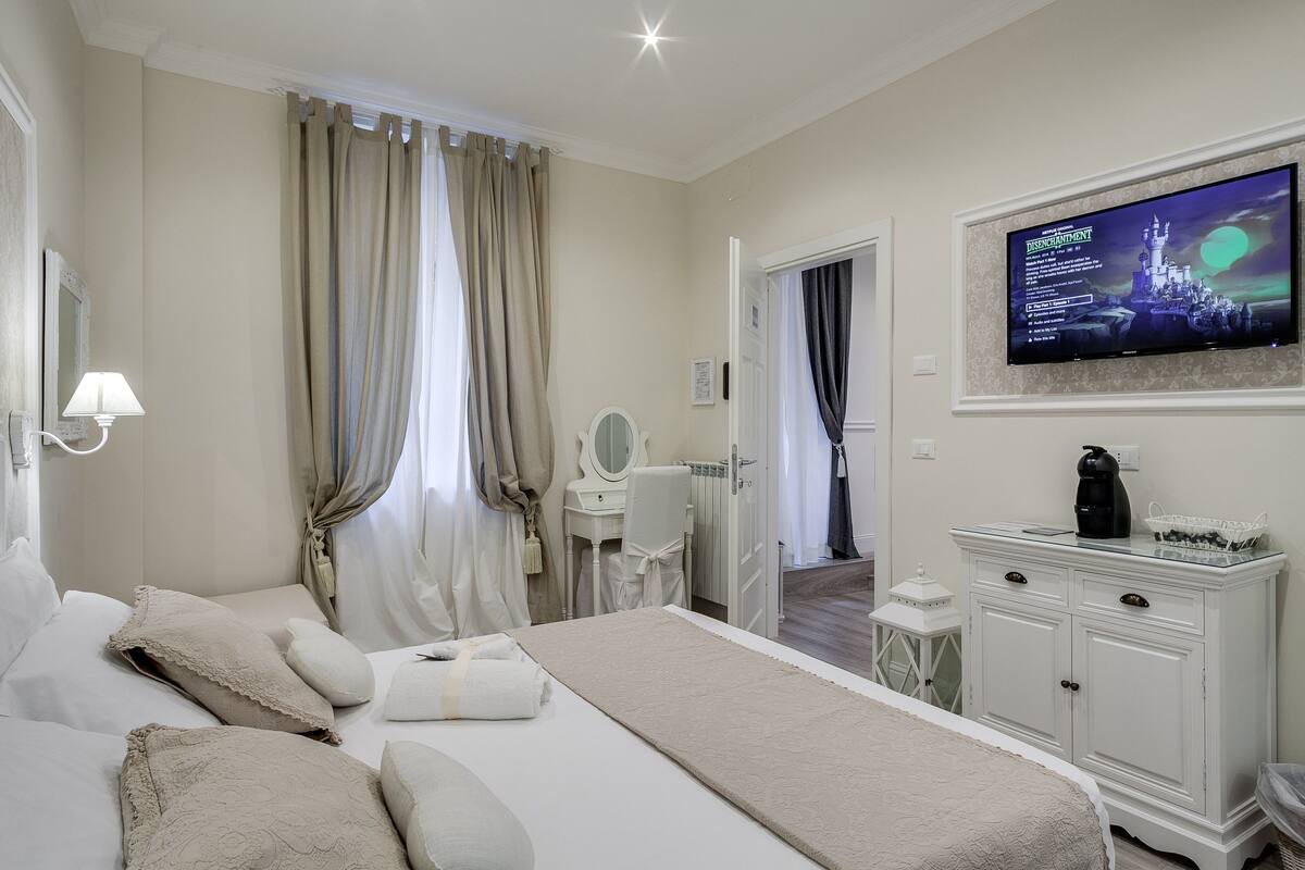 A hotel room with a large bed, a television mounted on the wall, a dresser, and a mirror.