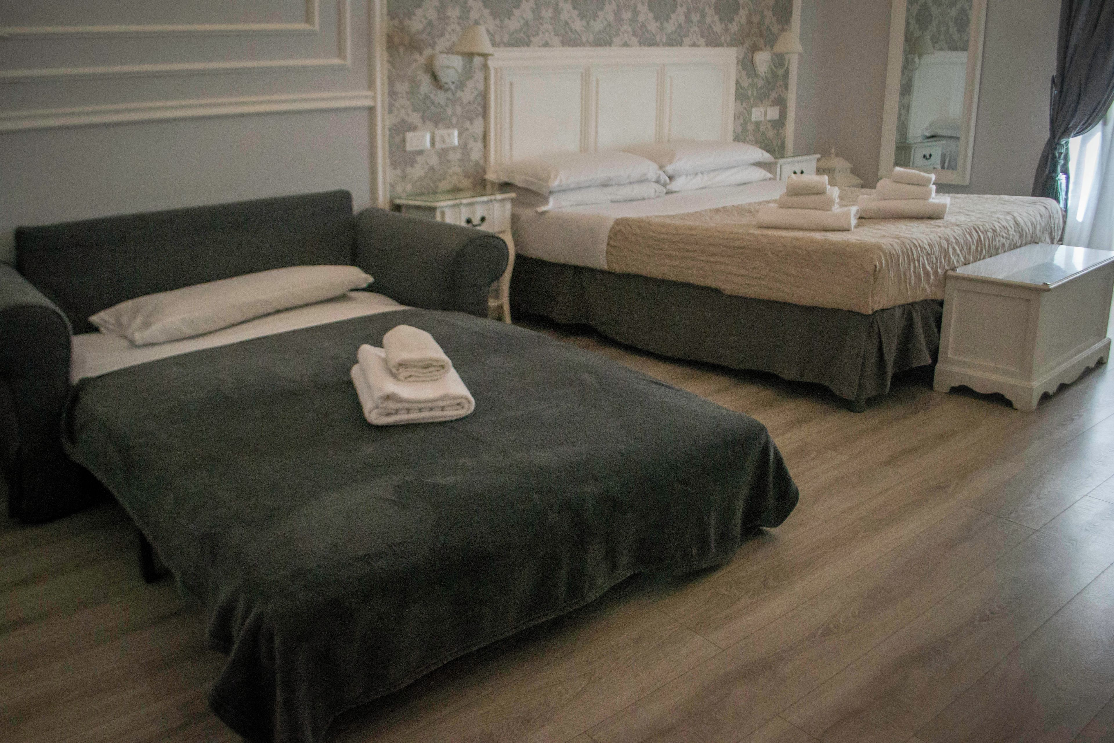 Habitació d'hotel amb dos llits, una tauleta de nit, un armari i una làmpada.