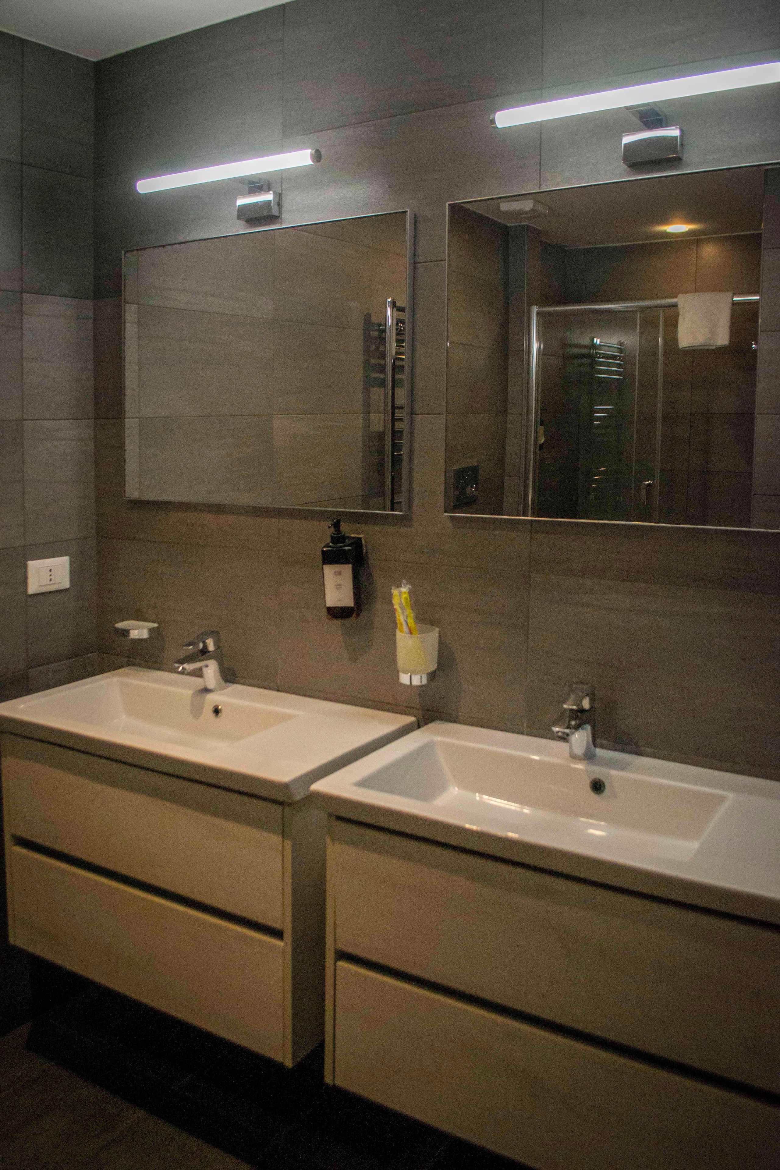 A modern bathroom with two sinks, a mirror, and a towel rack.