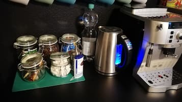 A kitchen counter with a coffee machine, jars of coffee beans, a water bottle, and a coffee pot.