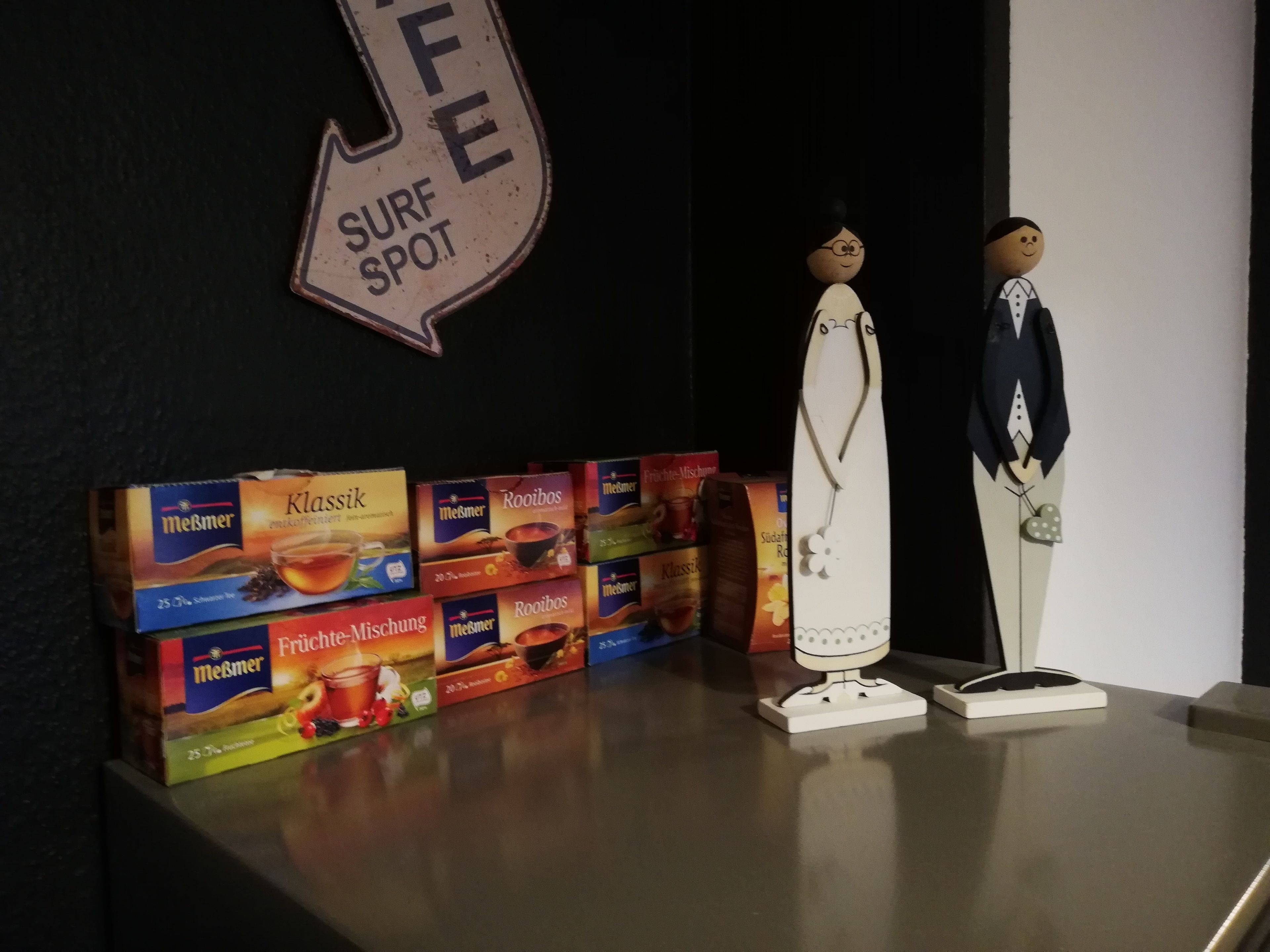 A shelf with boxes of Meßmer coffee and a surf spot sign.