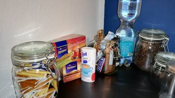 A kitchen counter with various food items and containers, including a box of Meßmer fruit mix, a jar of coffee, and several glass jars.