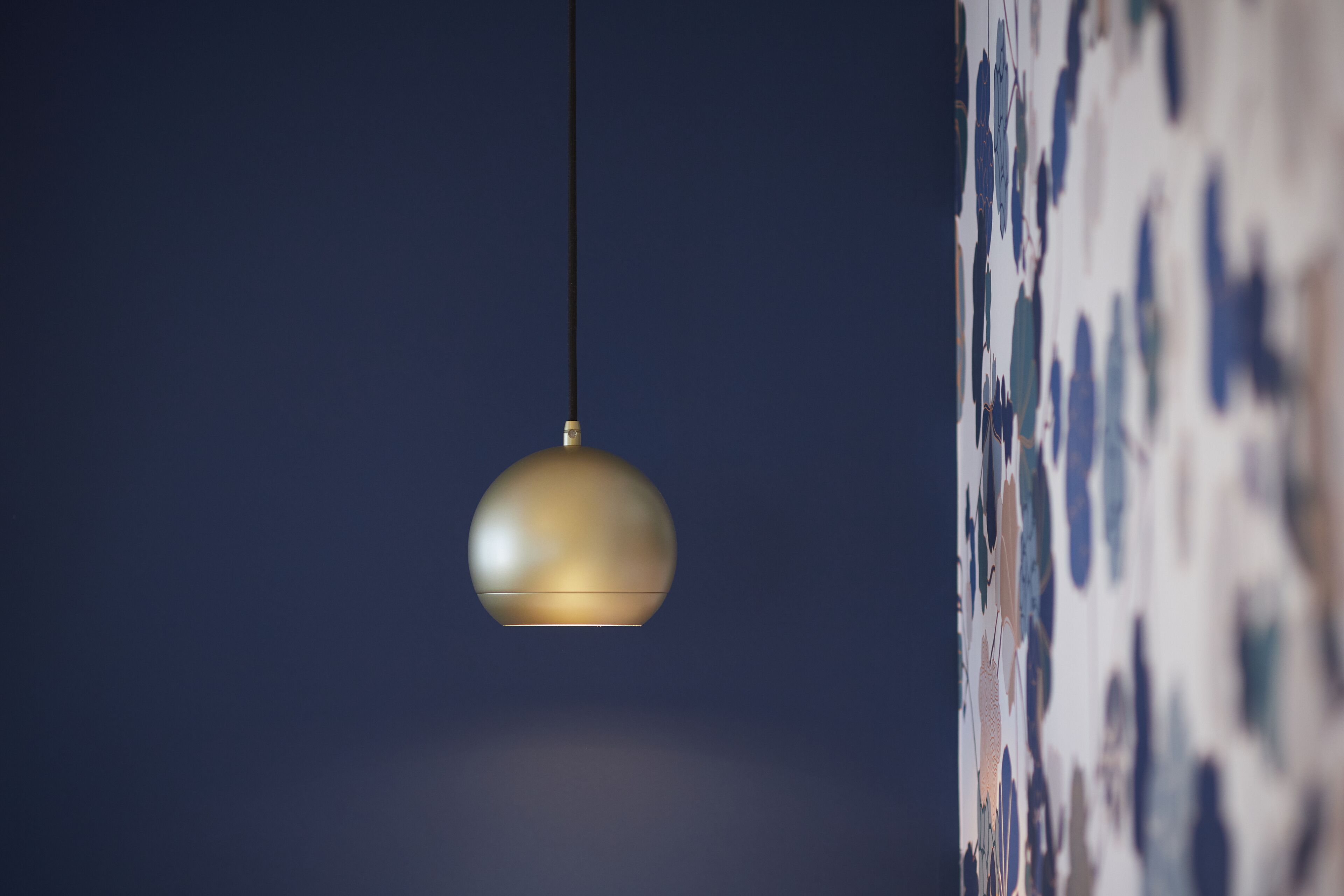 A hanging spherical light fixture against a dark background.