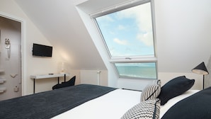 Een slaapkamer met dakraam, een bed, een bureau en een televisie.