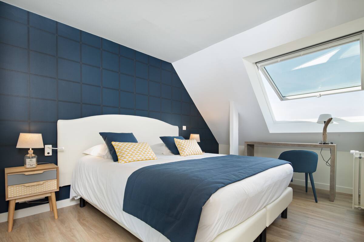 Un dormitorio moderno con una cama grande, un escritorio y un tragaluz.