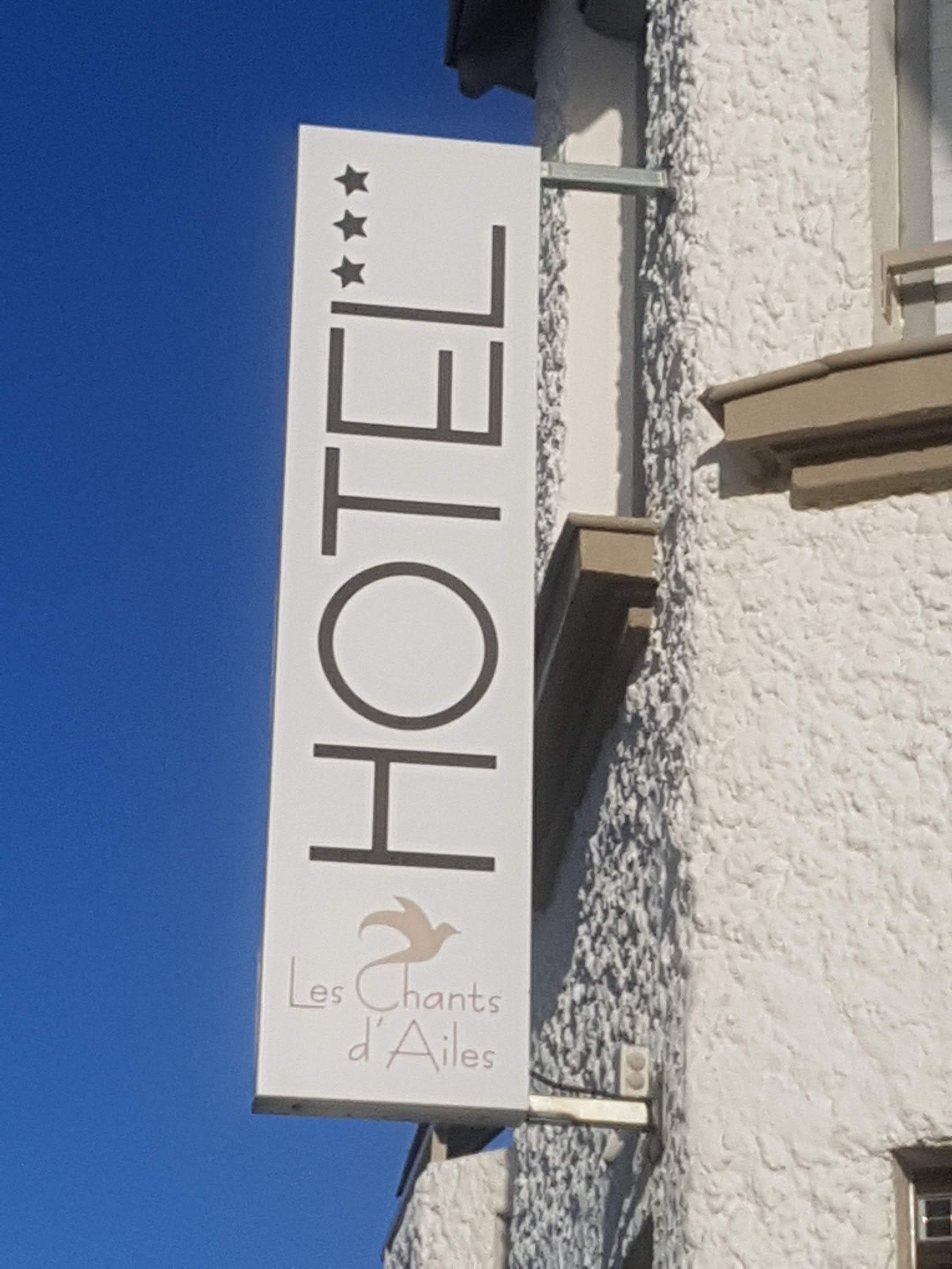 Un letrero de hotel con el nombre 'HOTEL' y 'Les Chants d'Ailes' debajo.
