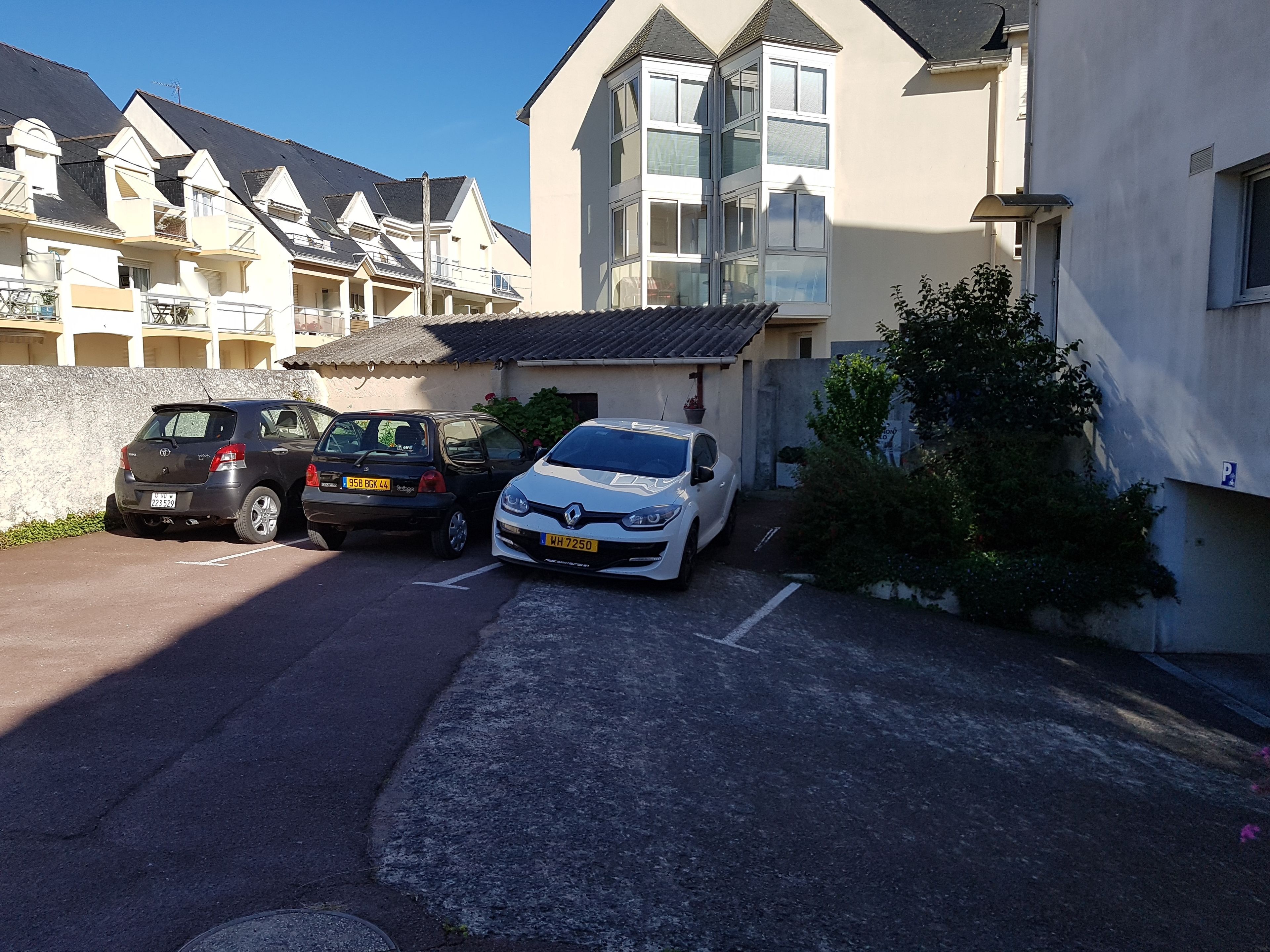 A residential area with two parked cars, a white Renault, and a black Toyota.