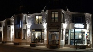 Een hotel met een structuurrijke gevel, meerdere ramen en een bord waarop staat dat het een hotel is.