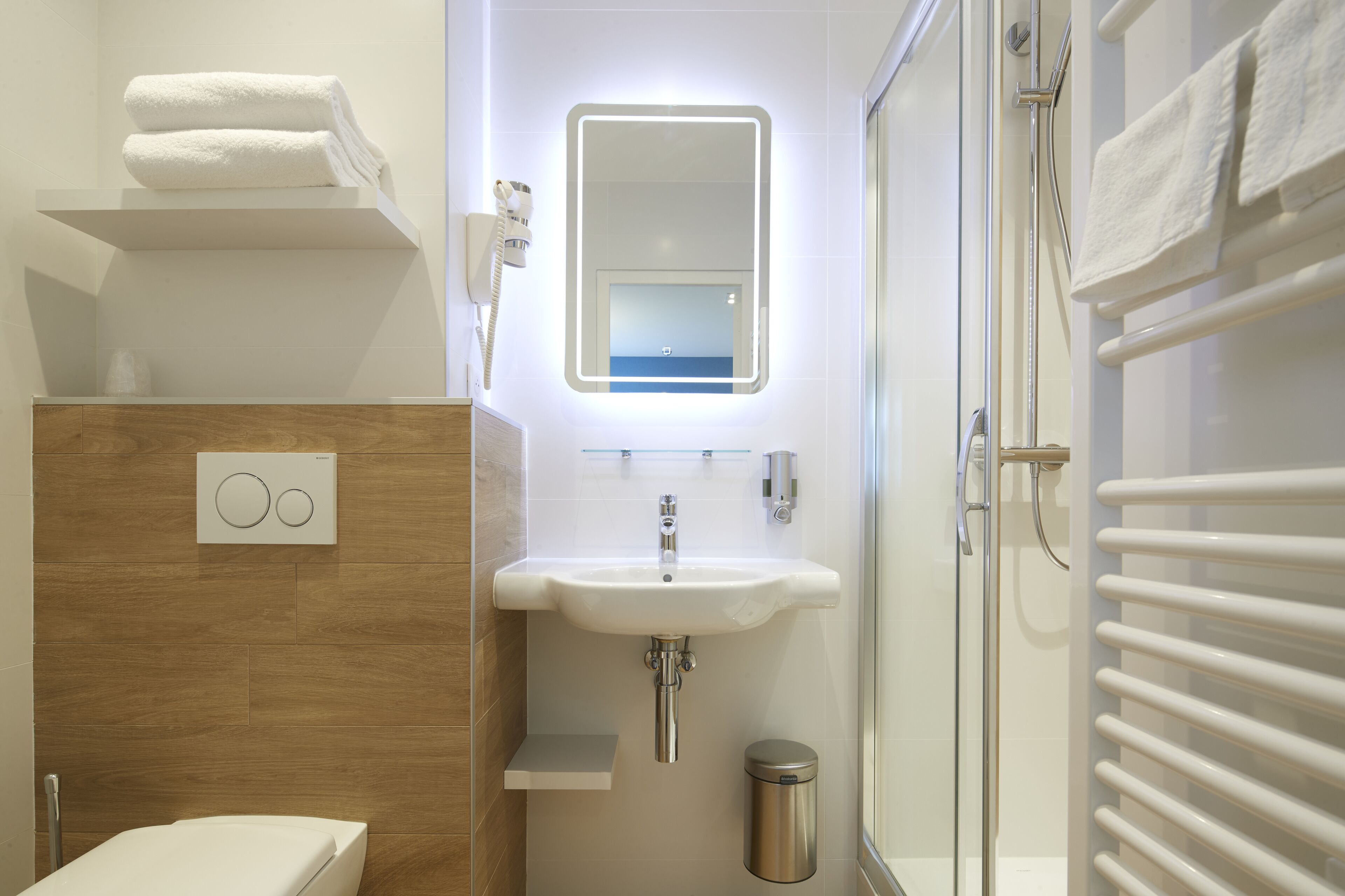 Een moderne badkamer met een witte wastafel, spiegel en handdoekhouder.