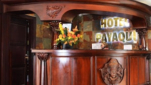 A reception desk with a 'HOTEL PAYAQUIL' sign, a vase with flowers, and a coat hanging on the wall. - Hotel Payaqui (Esquipulas)