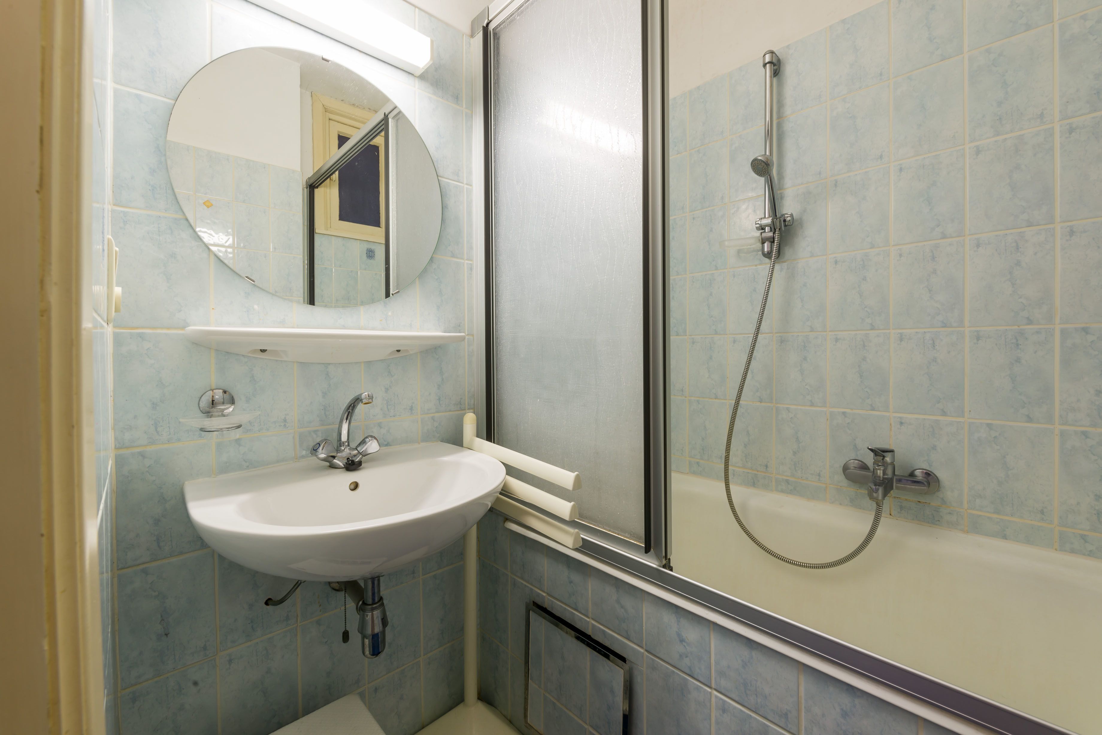 A bathroom with a sink, mirror, and shower.