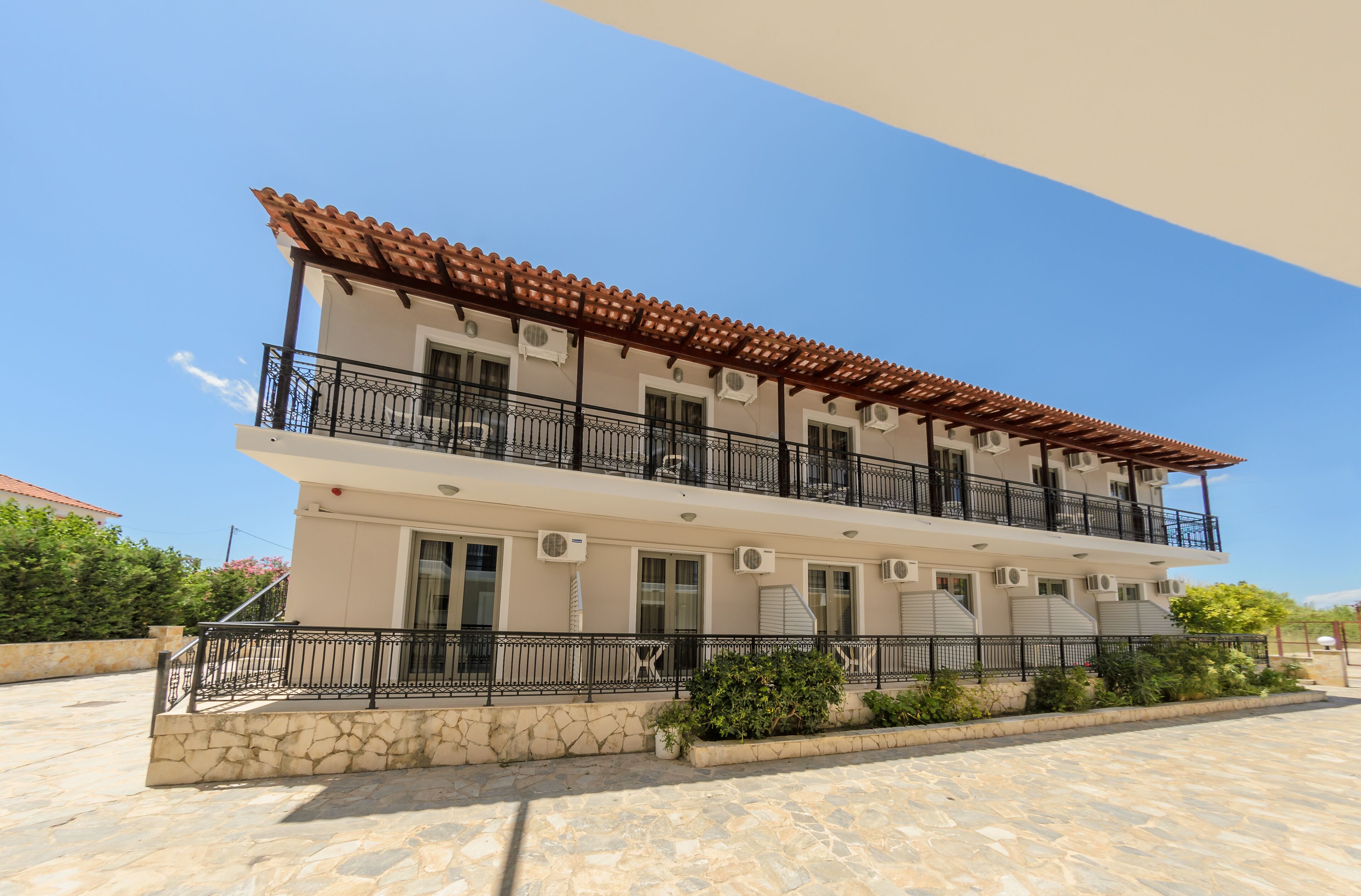 A two-story building with a tiled roof, balconies, and air conditioning units.