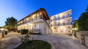 A two-story hotel with a central staircase, balconies, and a well-lit entrance. - Karras Livin (Zakynthos)