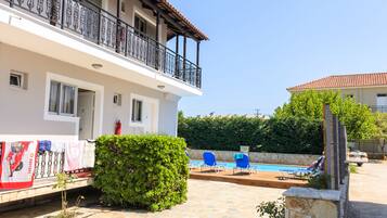 Ein zweigeschossiges Gebäude mit Balkon, Schwimmbad und Garten.