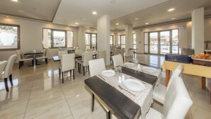 A spacious dining area with multiple tables and chairs, large windows, and a view of the outside. - Karras Livin (Zakynthos)