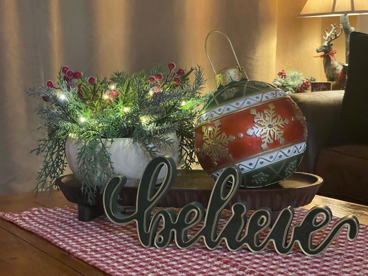 A decorative Christmas tree with lights and ornaments, a red and white ornament, and a 'Merry Christmas' sign on a table.