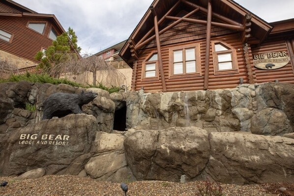 A log cabin building with a bear enclosure in front.