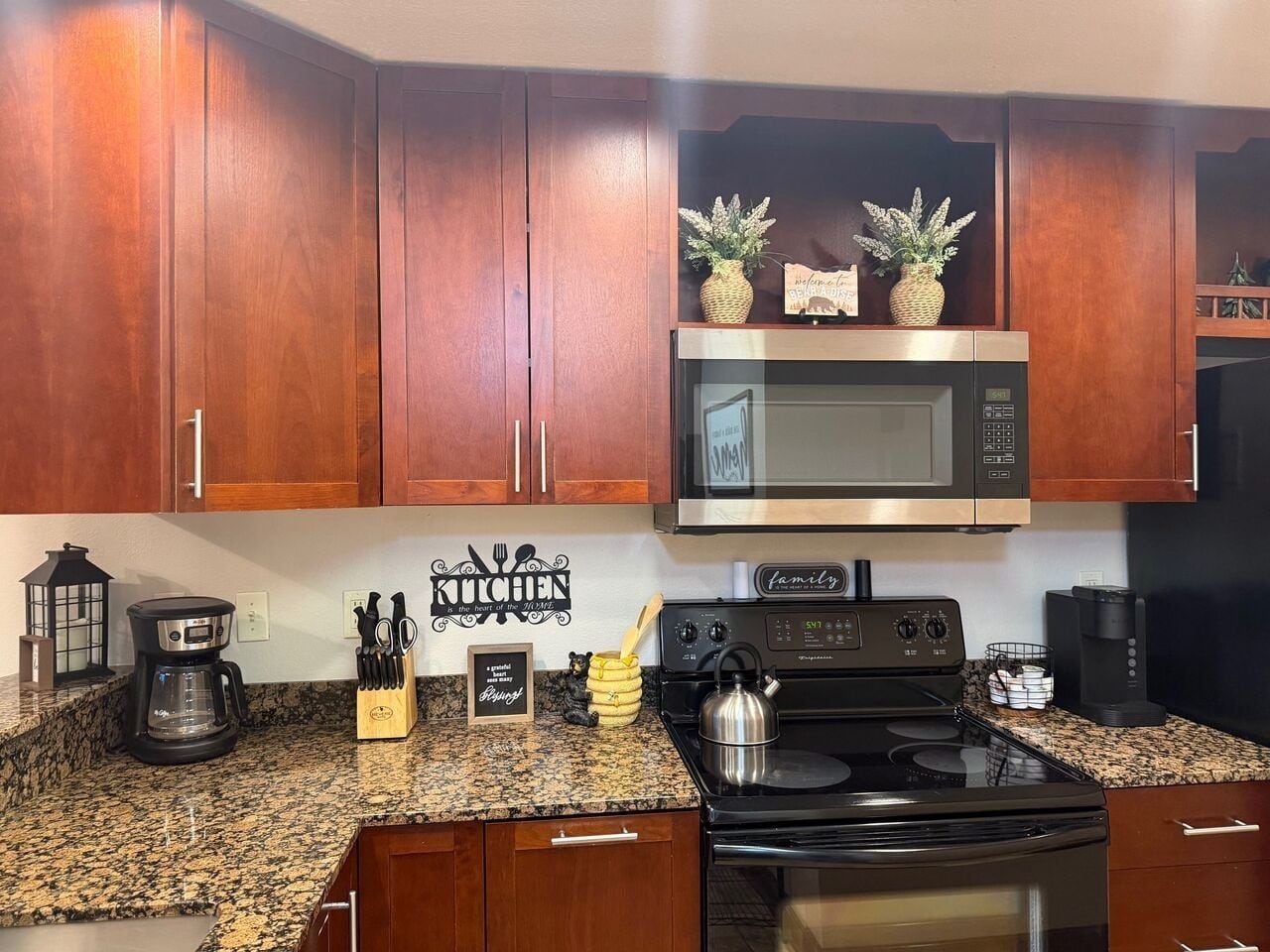 A kitchen with wooden cabinets, a microwave, a stove, and a coffee maker.