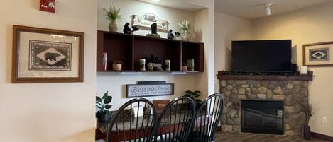 Una sala de estar con chimenea, televisor y comedor con sillas y mesa.