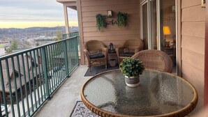 Ein Balkon mit Korbmöbeln, einem Glastisch und einem Blumentopf.