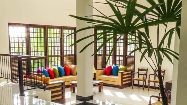 A spacious indoor area with a central pebbled floor, surrounded by seating areas with colorful cushions. - The Tamarind (Kandy)
