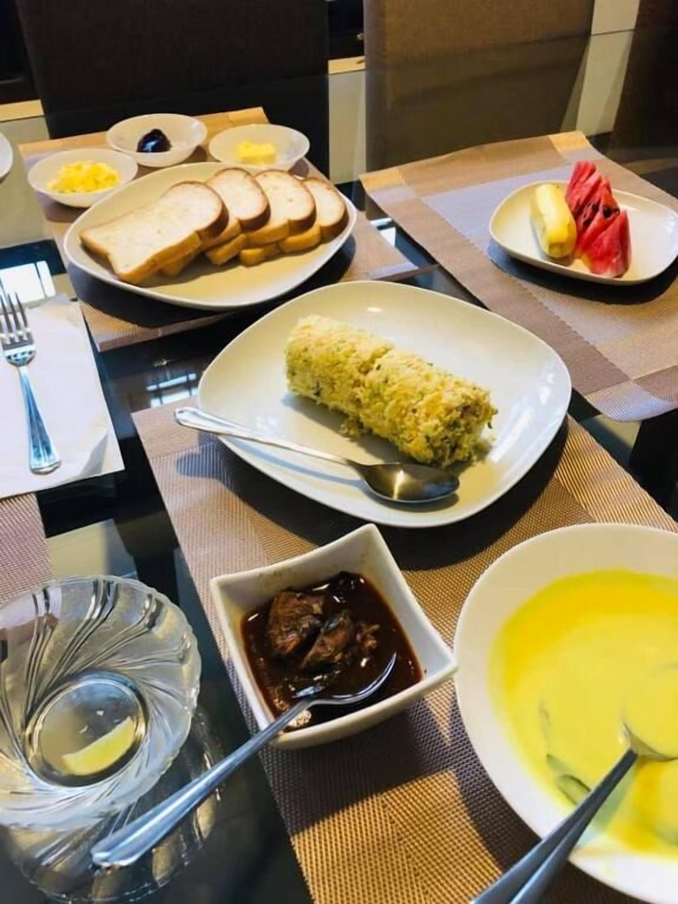 Een eettafel met verschillende gerechten, waaronder rijst, brood en een schaal met saus.