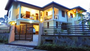 A two-story house with a gated entrance, a balcony on the upper floor, and a stone wall surrounding the property. - The Tamarind (Kandy)