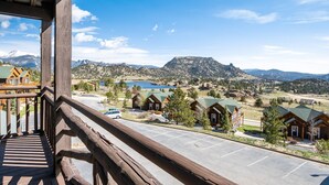 A view from a balcony overlooking a mountain resort with wooden cabins and a parking lot. - Powell Peak 104 1 Bedroom Condo by RedAwning (Estes Park)