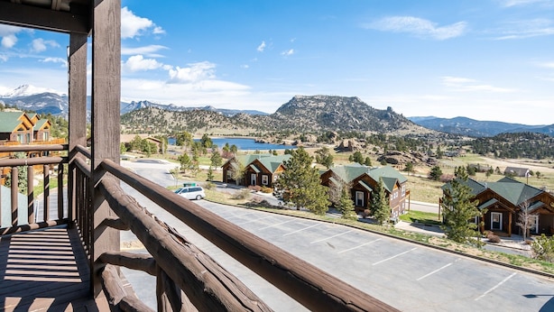 A view from a balcony overlooking a mountain resort with wooden cabins and a parking lot. - Powell Peak 104 1 Bedroom Condo by RedAwning (Estes Park)