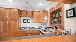 A kitchen with wooden cabinets, a microwave, a stove, and a sink. - Powell Peak 104 1 Bedroom Condo by RedAwning (Estes Park)