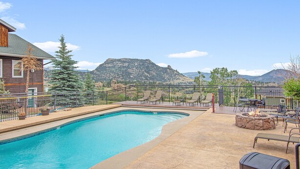 A swimming pool with a stone deck, outdoor seating, and a mountain view. - Powell Peak 104 1 Bedroom Condo by RedAwning (Estes Park)