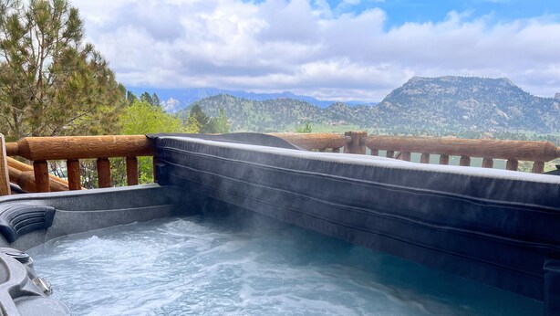 A hot tub with a wooden deck and a view of mountains.
