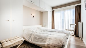A modern bedroom with a bed, a bedside table, a chair, and a wardrobe. - Kentucky 603 (Koksijde)