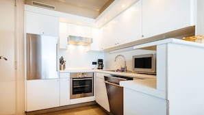A modern kitchen with white cabinets, stainless steel appliances, and a wooden floor. - Kentucky 603 (Koksijde)