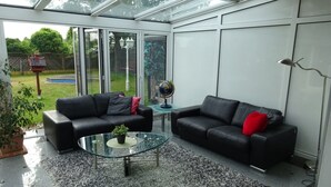 Una veranda con due divani in pelle nera, un tavolino in vetro e un piccolo mappamondo.