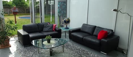 A conservatory with two black leather sofas, a glass coffee table, and a small globe.