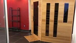 Una stanza con pavimento piastrellato, parete rossa e un pannello divisorio in legno con finestre.