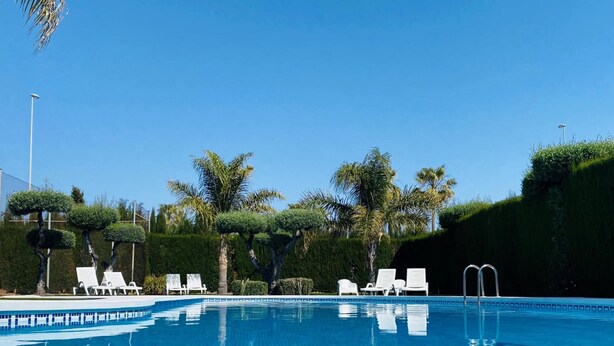 A clear blue pool with white lounge chairs and a well-maintained hedge. - Hotel Playa Canet (Canet de Berenguer)