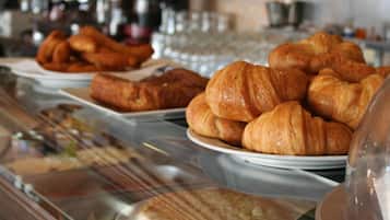 Una vitrina de panadería con diversas opciones de productos horneados, incluyendo croissants y pasteles.
