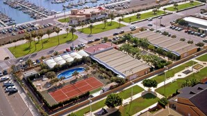 An aerial view of a marina with boats, a swimming pool, tennis courts, and a parking lot. - Hotel Playa Canet (Canet de Berenguer)