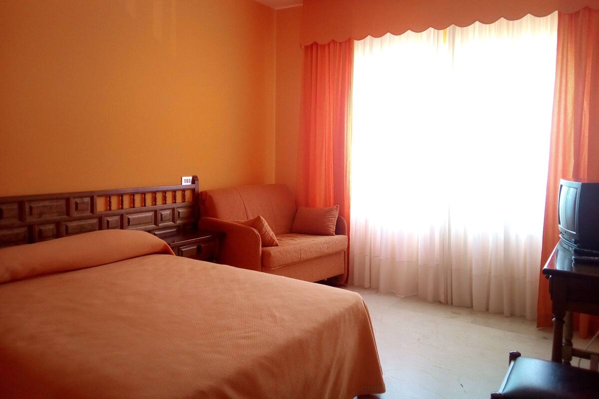Habitación de hotel con dos camas, un escritorio y una televisión.